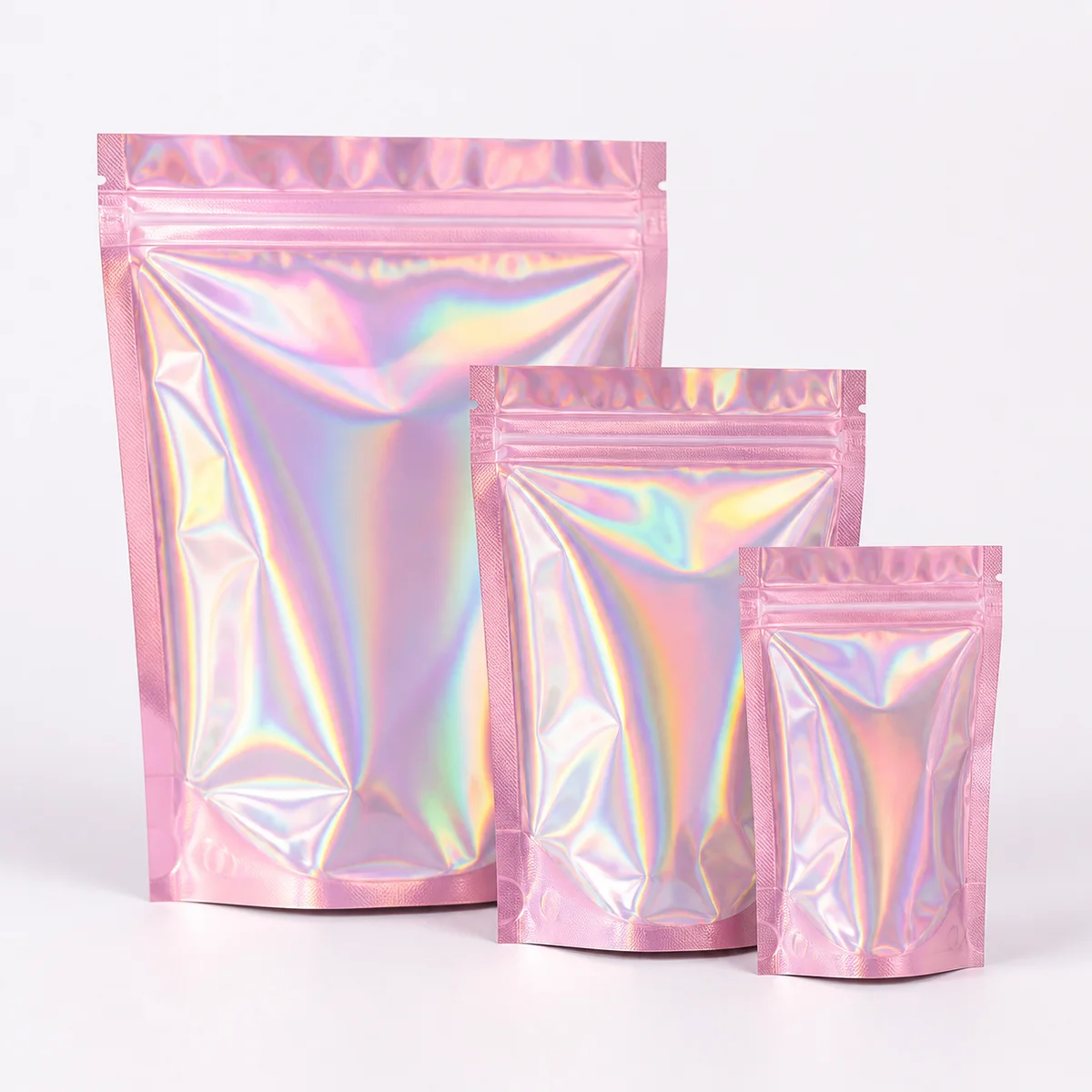 Empty pink holographic zipper bags in three sizes.